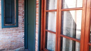 A brick building with a green door and a window with a wooden frame. - El Rinconcito (Puerto Iguazú)