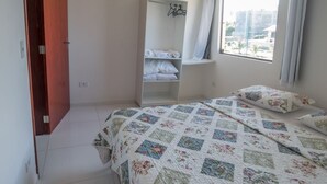 A bedroom with a bed, a wardrobe, a window, and a view of buildings outside. - Flats Vieiras do Maragogi (Maragogi)