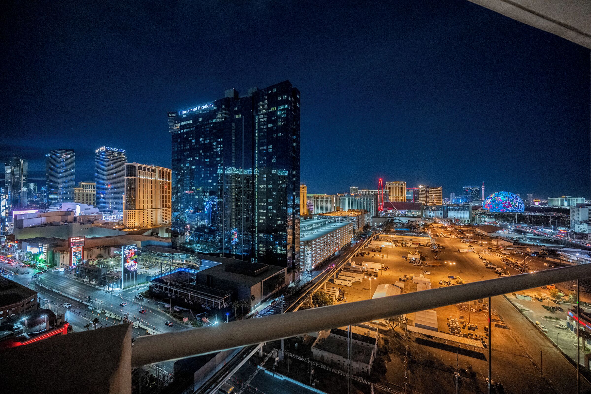 A nighttime cityscape with illuminated skyscrapers, including a prominent Hilton Grand Vacations building.