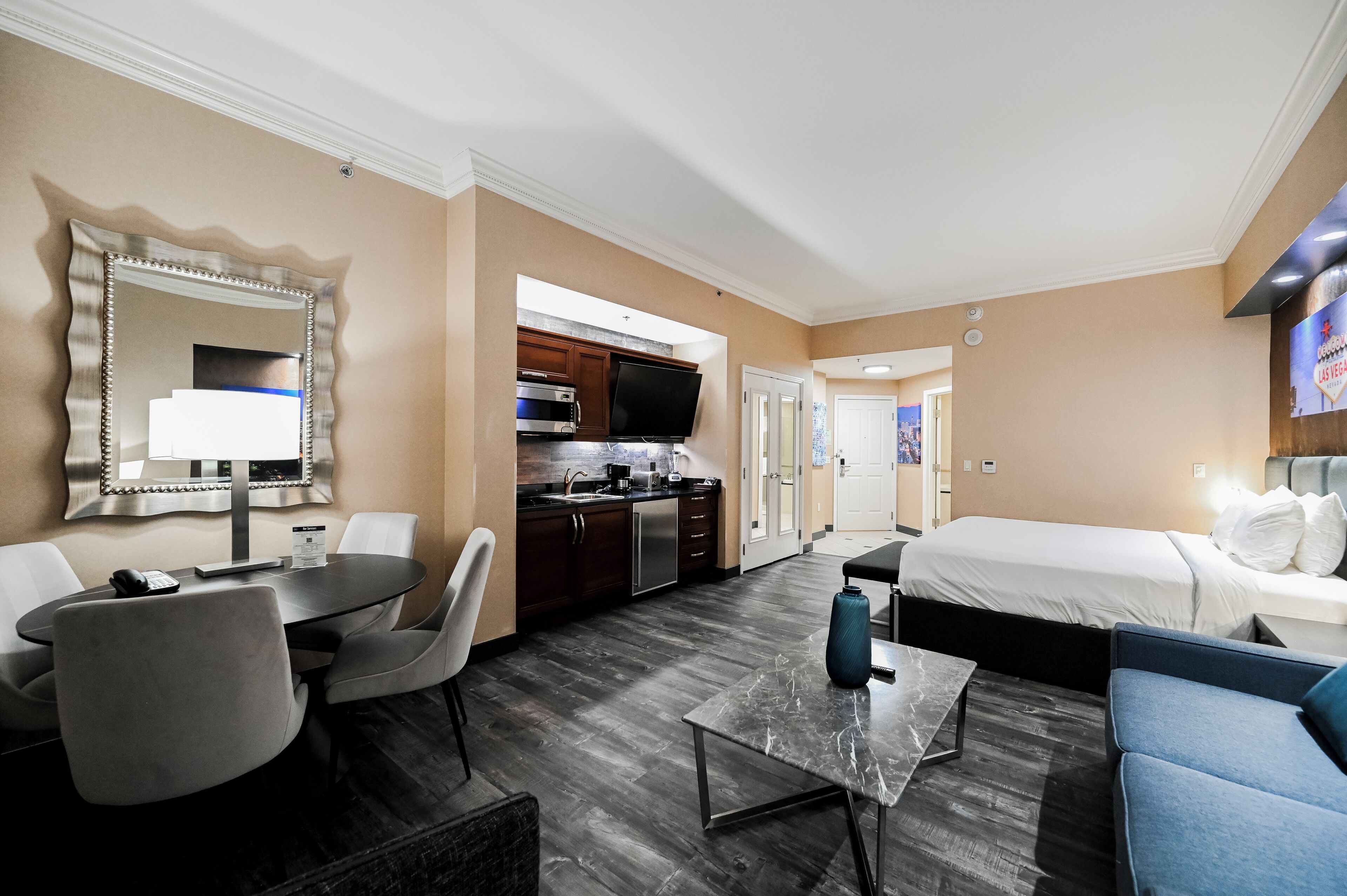 A hotel room with a dining area, kitchenette, and a bed.