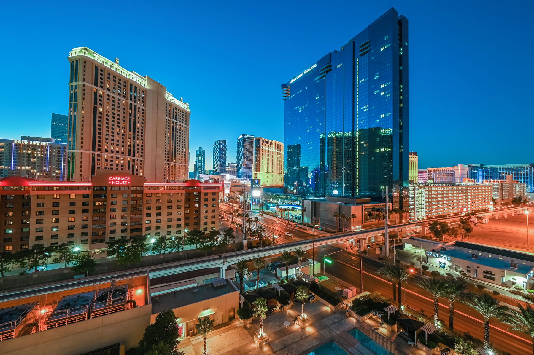 A high-rise hotel with multiple floors and a prominent glass facade, located in a cityscape with other buildings and a busy street below.