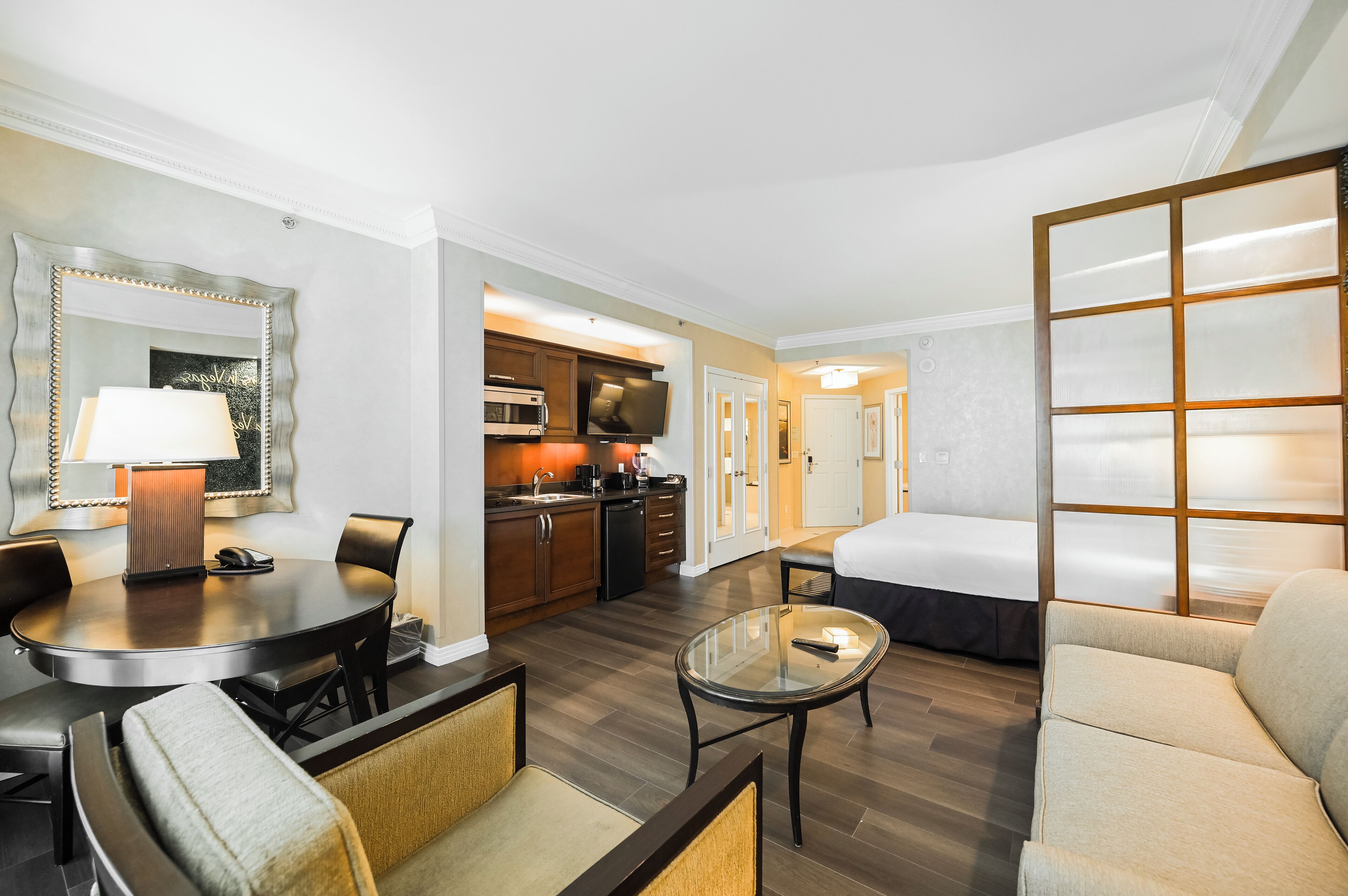 A hotel room with a dining area, kitchenette, and a bed.