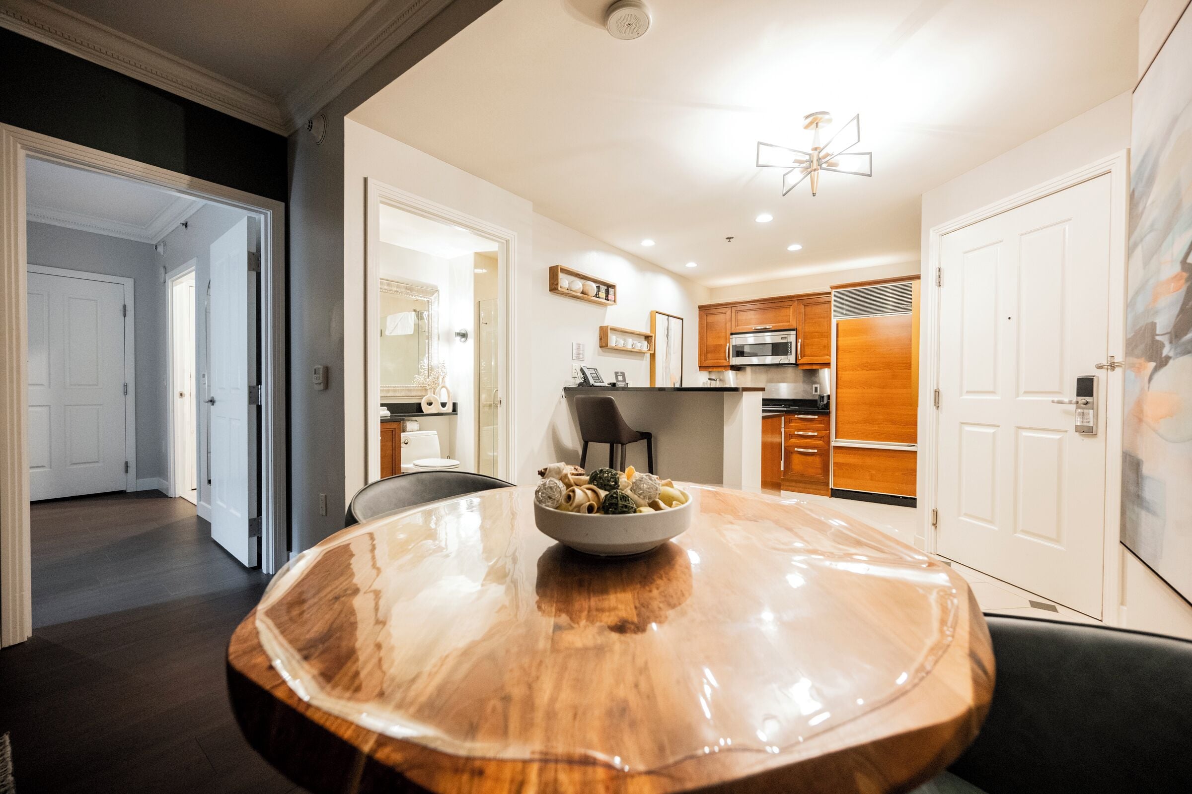 Een moderne keuken met houten kastjes, een RVS magnetron en een eethoek met een houten tafel en stoelen.