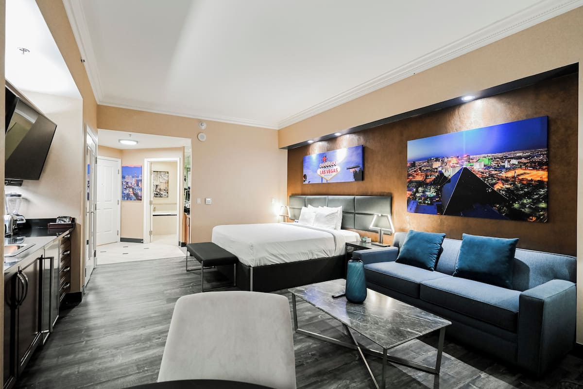 A modern hotel room with a bed, sofa, and a TV.