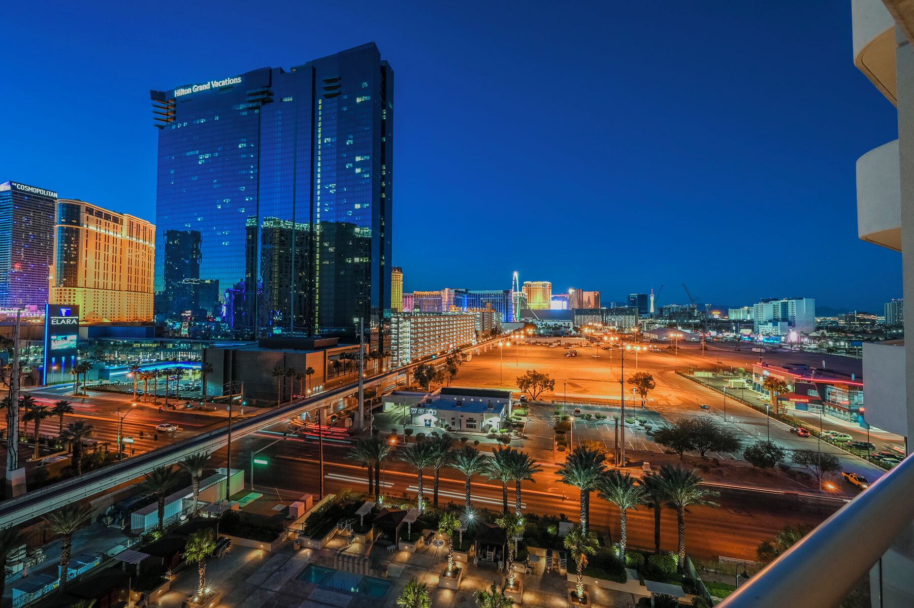 A nighttime cityscape with prominent buildings including Hilton Grand Vacations and Cosmopolitan hotels.