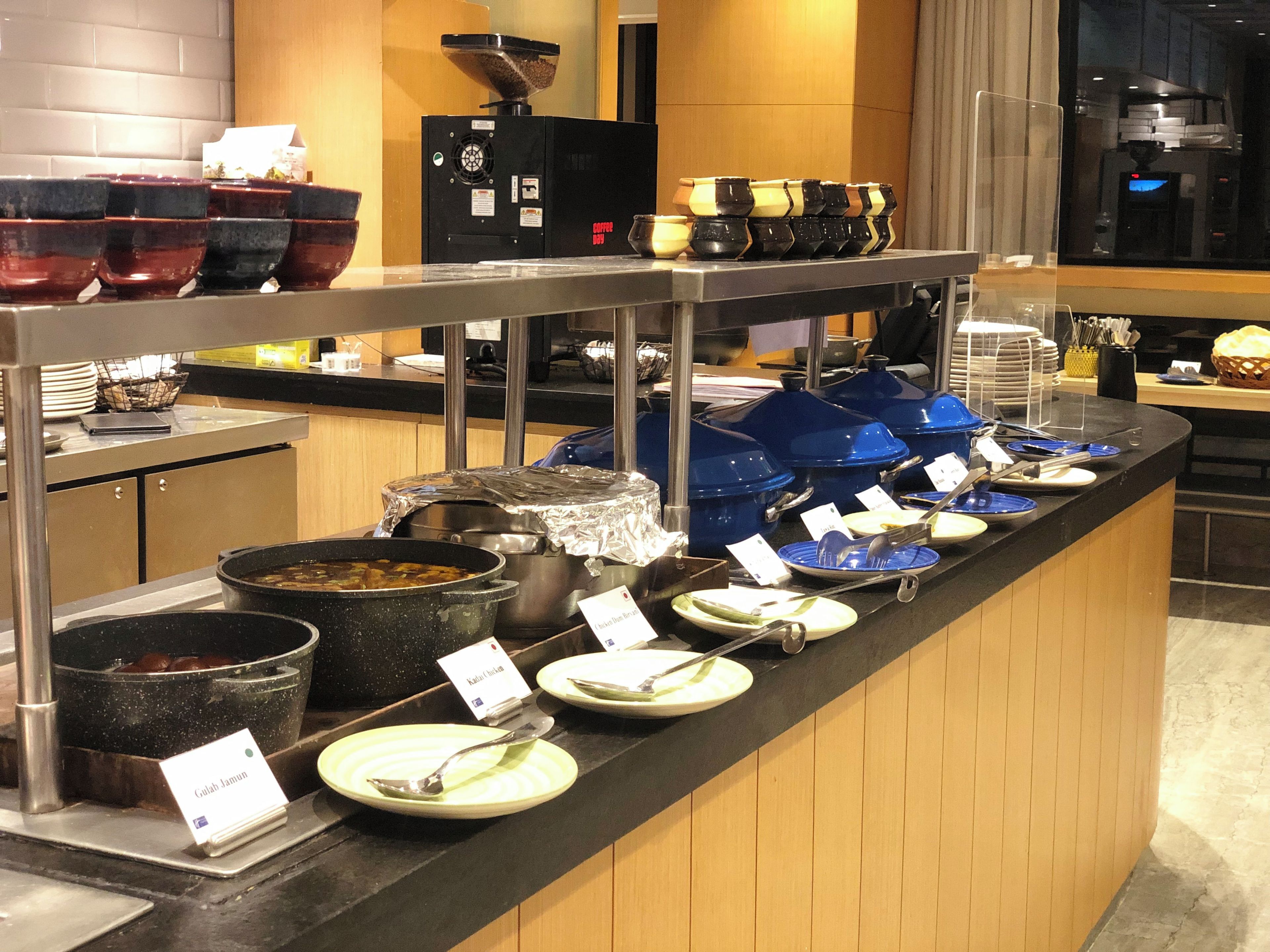 A buffet counter with various dishes and utensils.