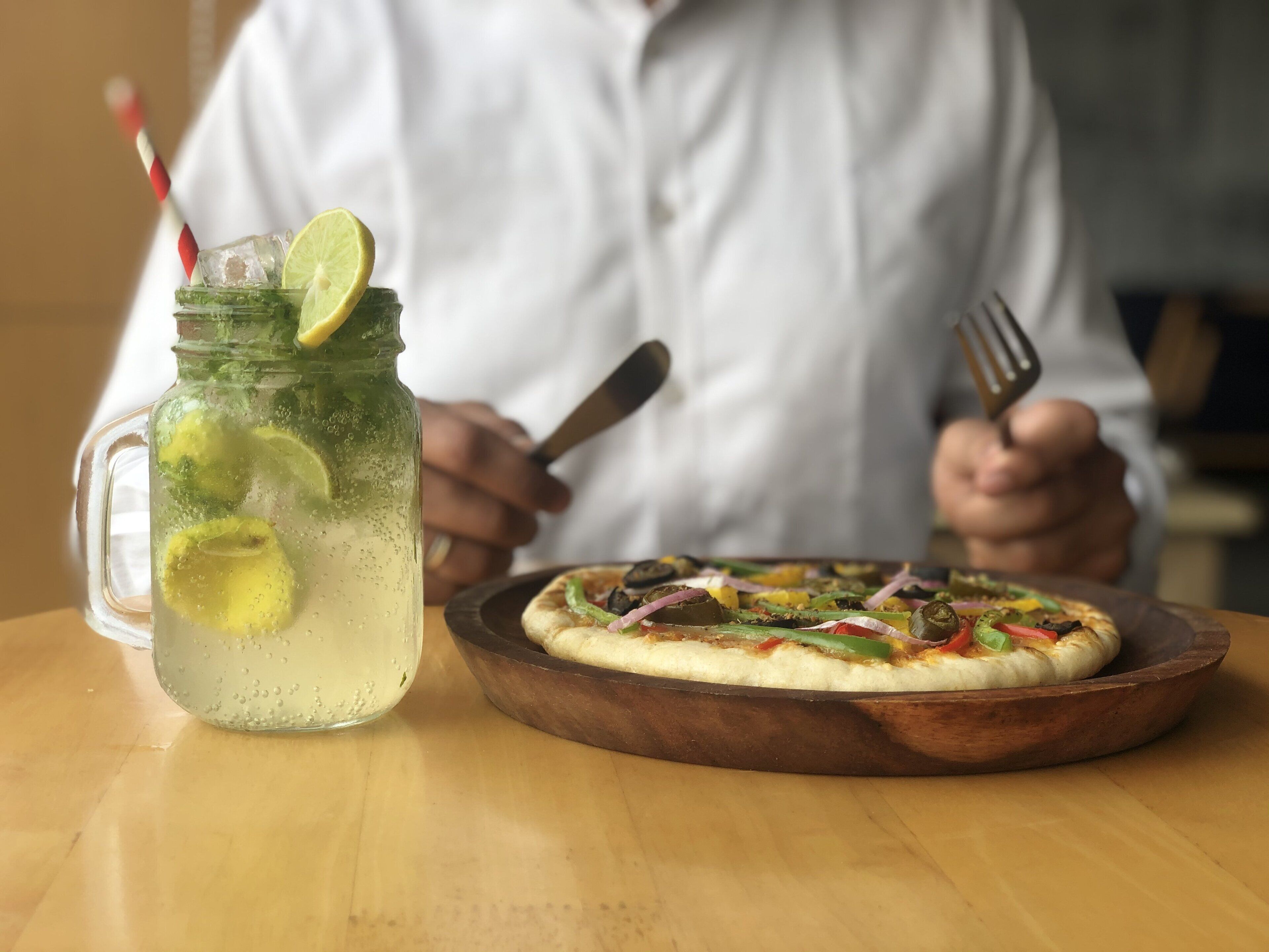 A person seated at a table with a meal and a drink.