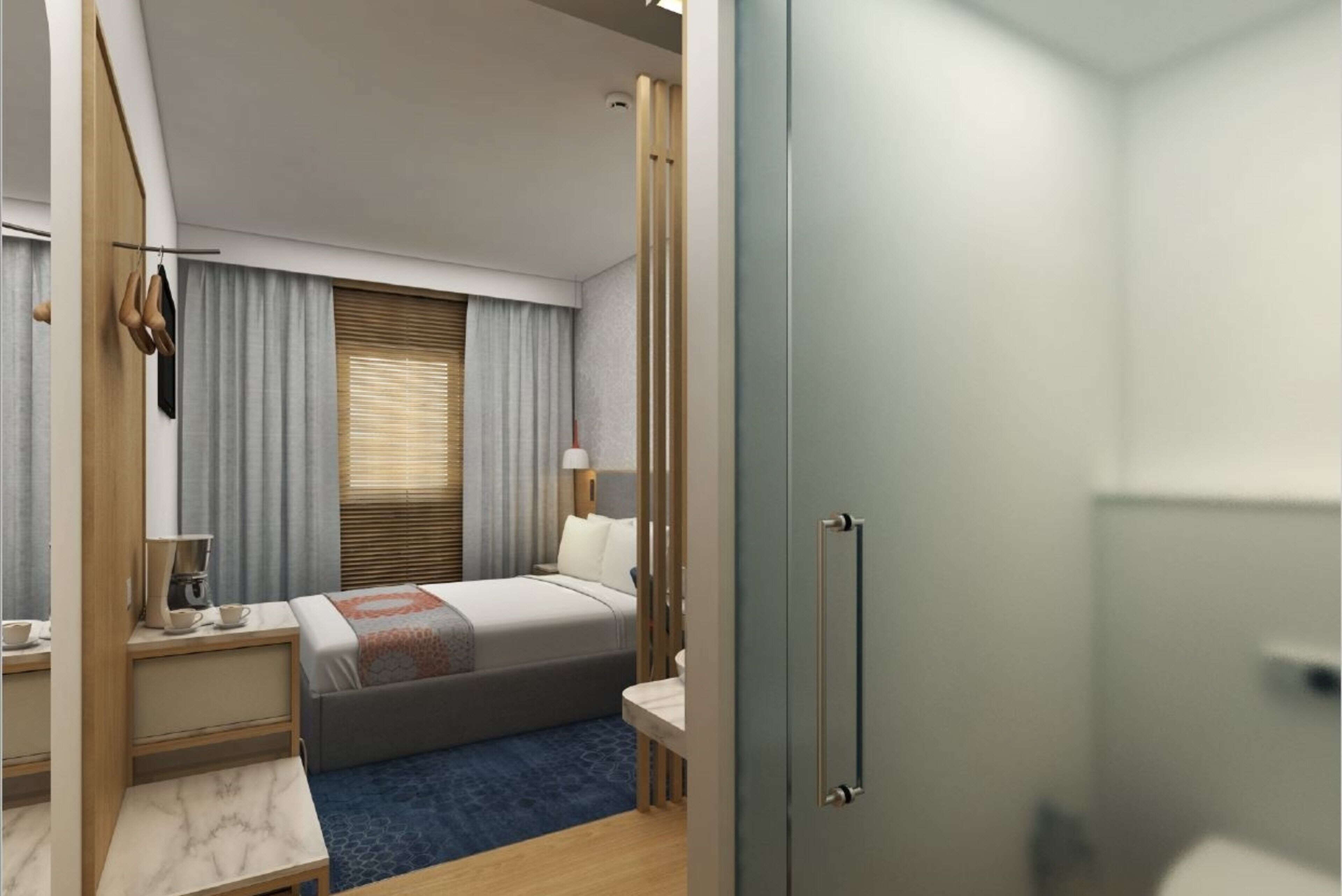 A hotel room with a bed, bedside table, lamp, and a wardrobe.