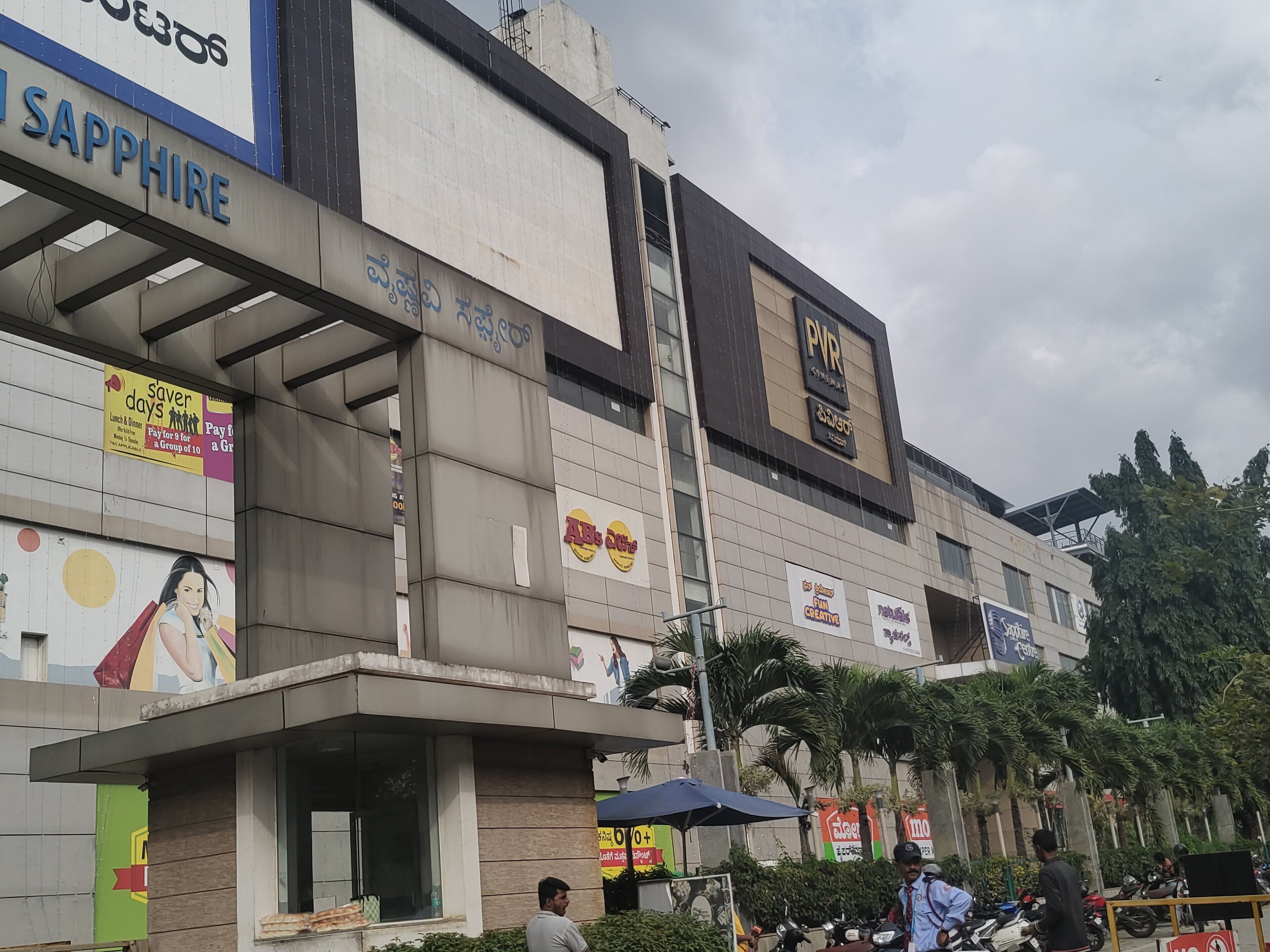 Un edificio de varios pisos con varios letreros comerciales, incluyendo un letrero 'Sapphire' y un cine 'PVR'.