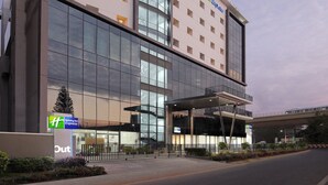 Ein Holiday Inn Express Hotel mit moderner Glasfassade, mehreren Balkonen und einem überdachten Eingang.
