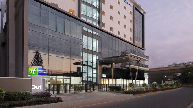 A Holiday Inn Express hotel with a modern glass facade, multiple balconies, and a covered entrance. - Holiday Inn Express Bengaluru Yeshwantpur by IHG (Bengaluru)