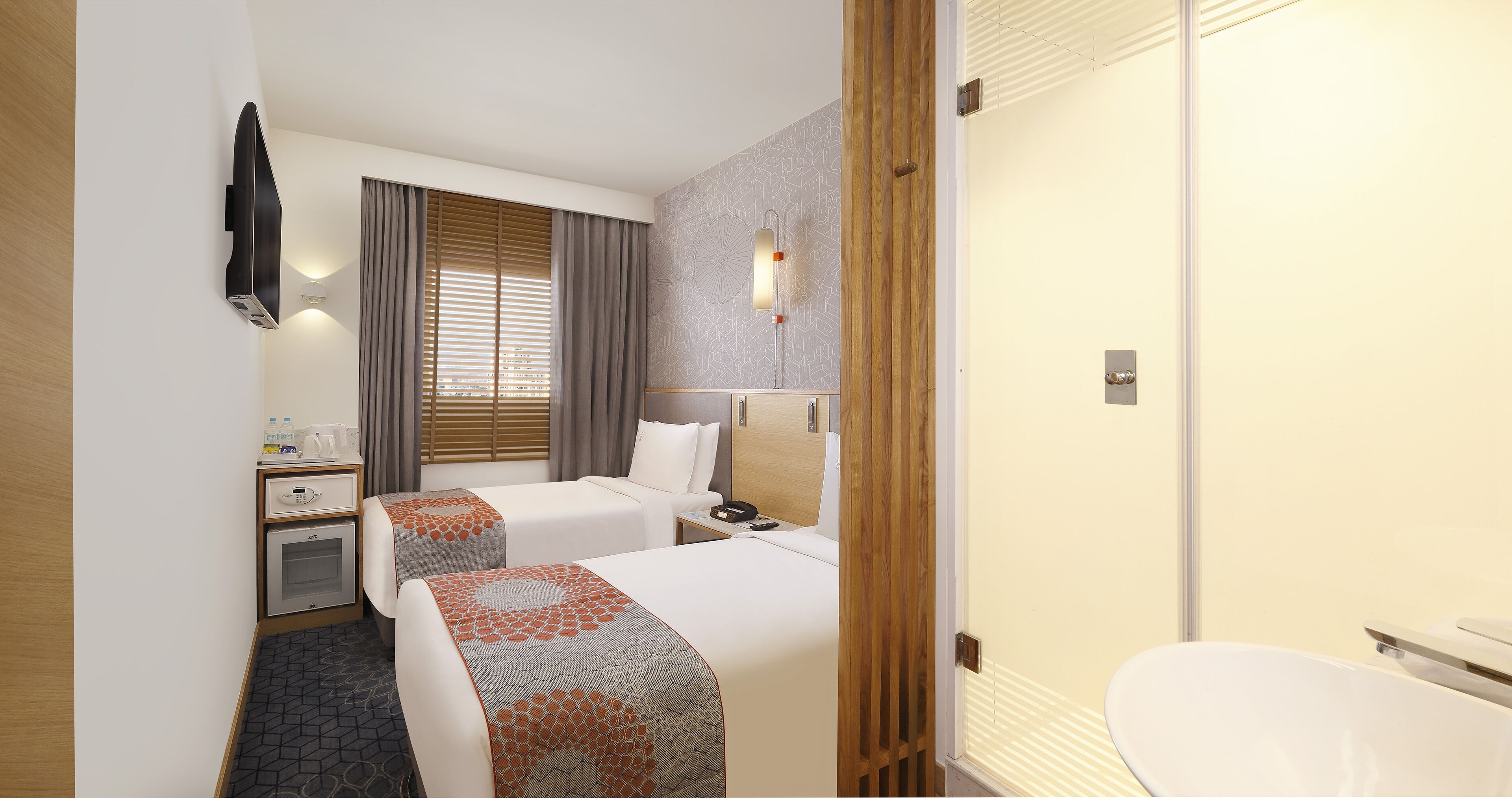 Habitación de hotel con dos camas, un escritorio, un minibar y baño.