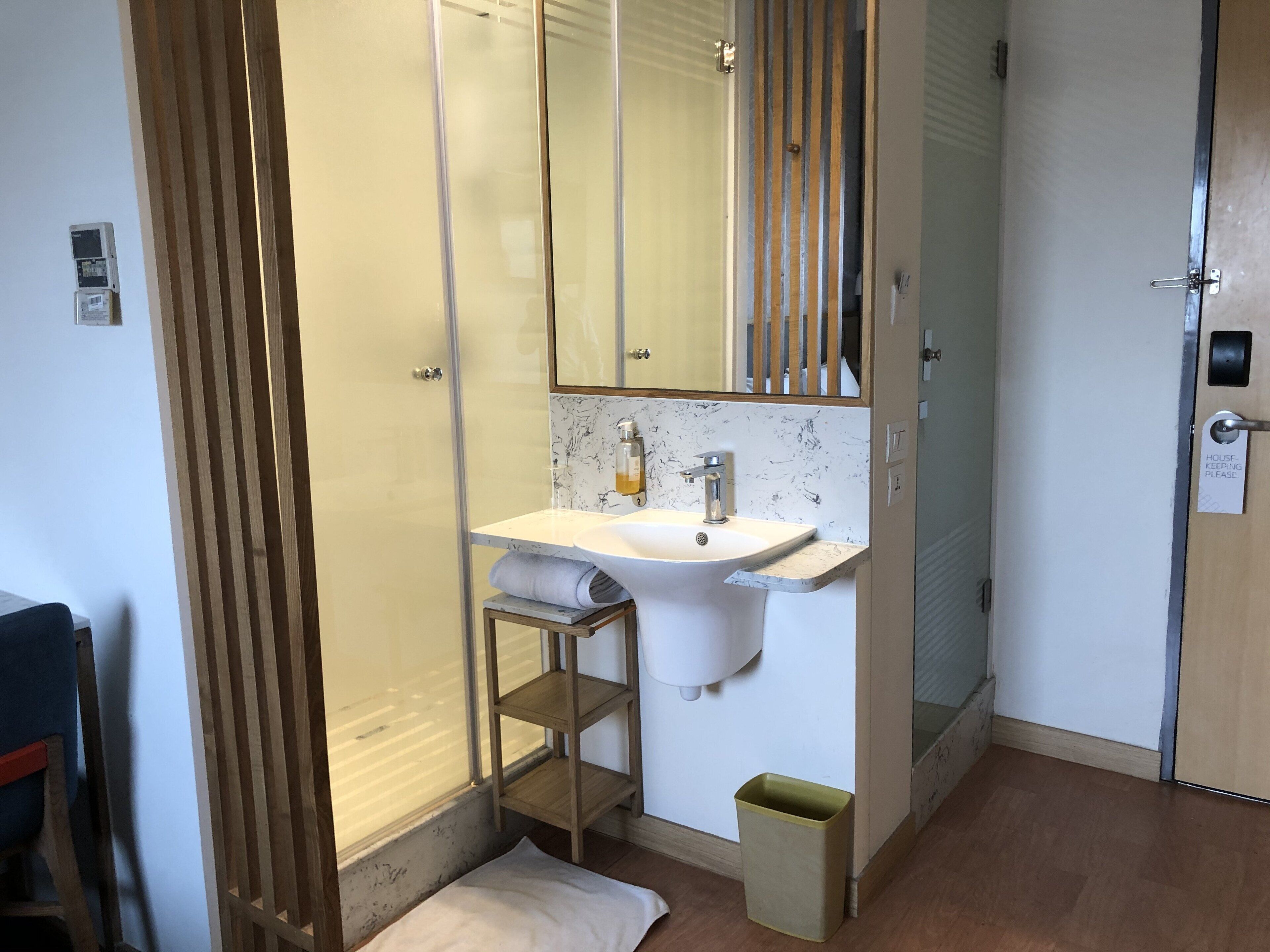 Un baño con lavamanos blanco, espejo y cabina de ducha.