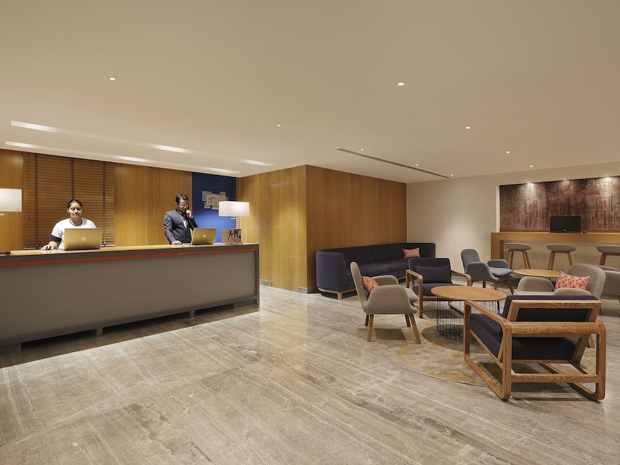 A modern reception area with a reception desk, seating area, and a large wall-mounted TV.