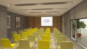 A conference room with yellow chairs arranged in rows, a large screen at the front, wooden panel walls, and a large window with a view of greenery. - Holiday Inn Express Bengaluru Yeshwantpur by IHG (Bengaluru)