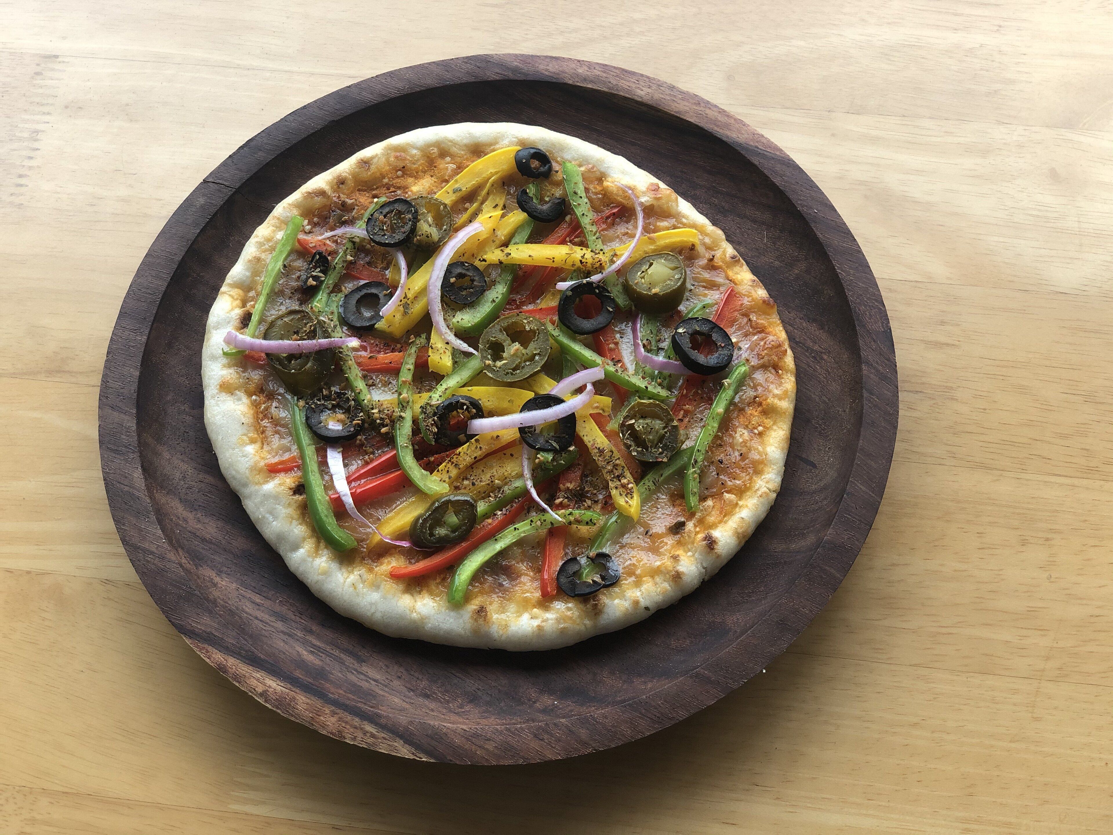 A pizza on a wooden plate.