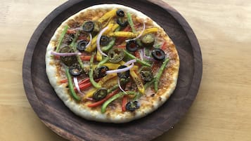 A pizza on a wooden plate.