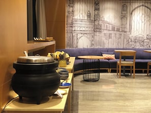 Un interior modern amb un sofà, una taula amb una olla i una paret amb un mural detallat.