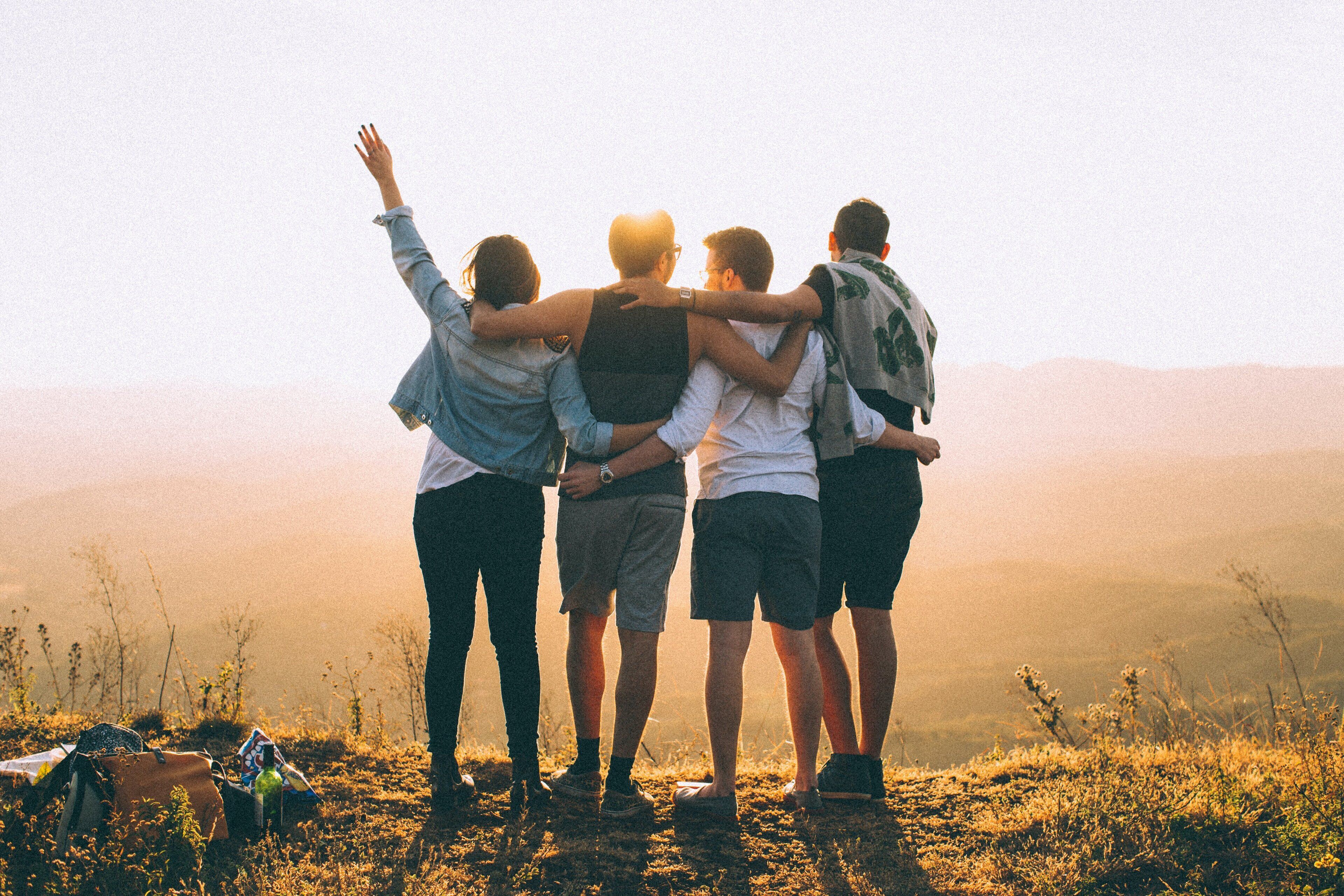 A group of people standing together on a grassy hill with a mountainous backdrop.