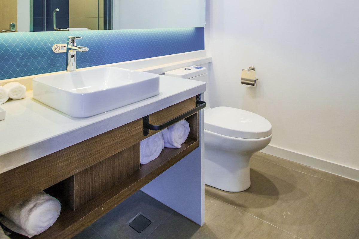 A modern bathroom with a white sink, mirror, and toilet.