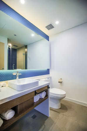 A modern bathroom with a white sink, mirror, and toilet.