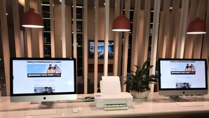 Una mesa de recepción con dos monitores, una impresora y una planta.
