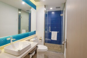 Un baño moderno con cabina de ducha de vidrio, un lavabo blanco y un inodoro.