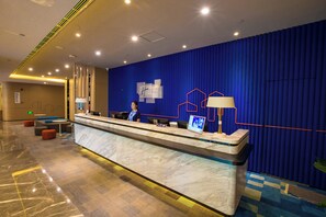 A hotel reception area with a marble counter, a receptionist, and a blue wall with a geometric design. - Holiday Inn Express Hefei High Tech by IHG (Hefei)