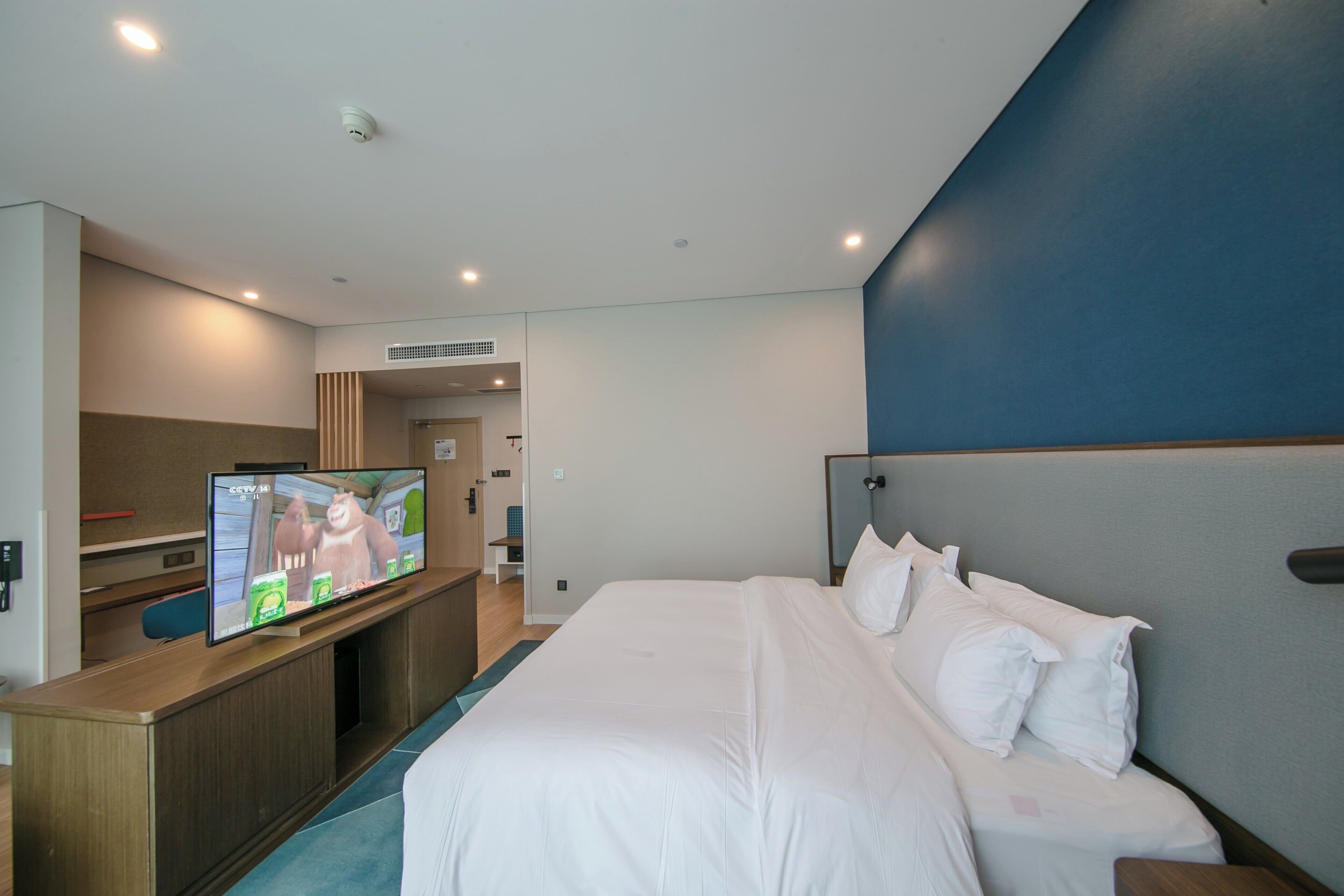 Una habitación de hotel con una cama, un escritorio con computadora y televisión.