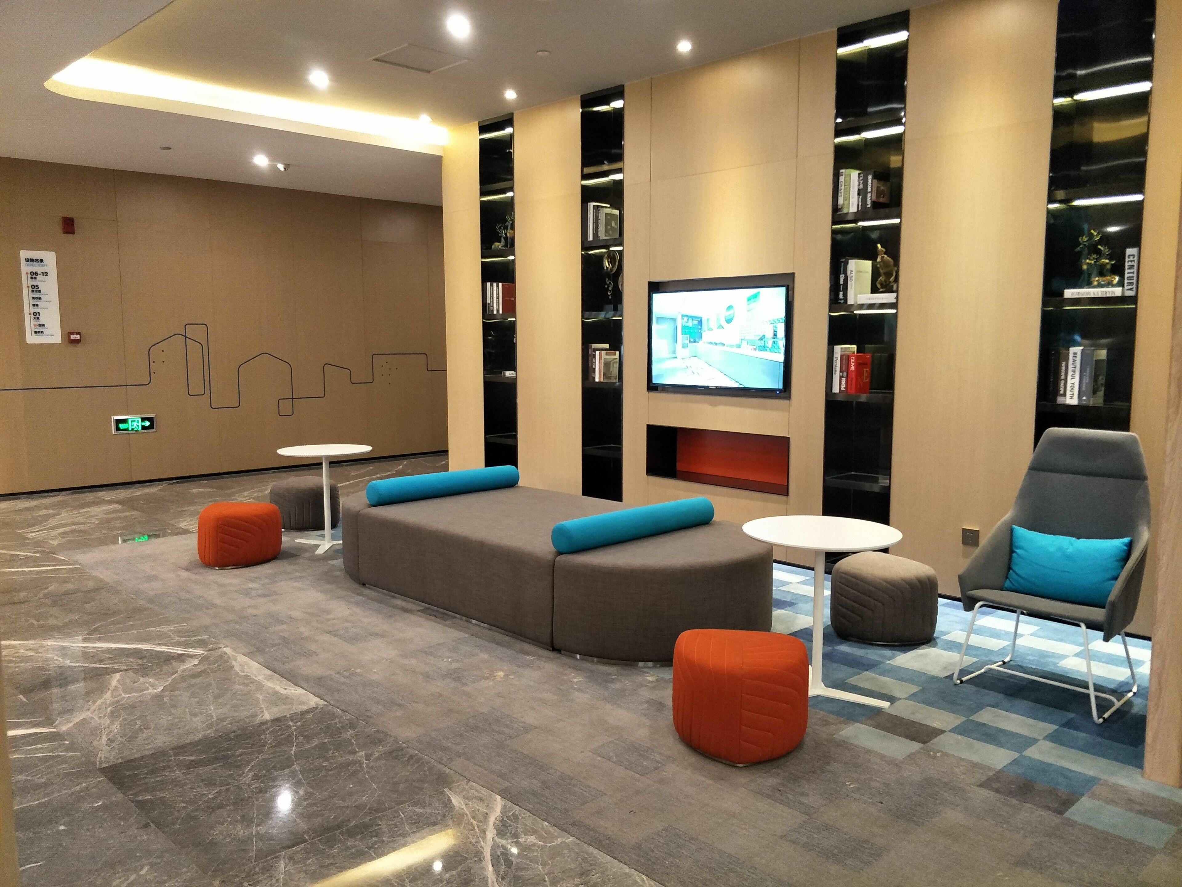 A modern lounge area with seating, a television, and bookshelves.