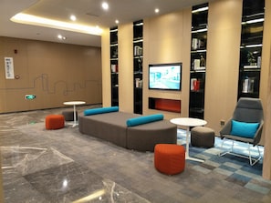A modern lounge area with seating, a television, and bookshelves. - Holiday Inn Express Hefei High Tech by IHG (Hefei)