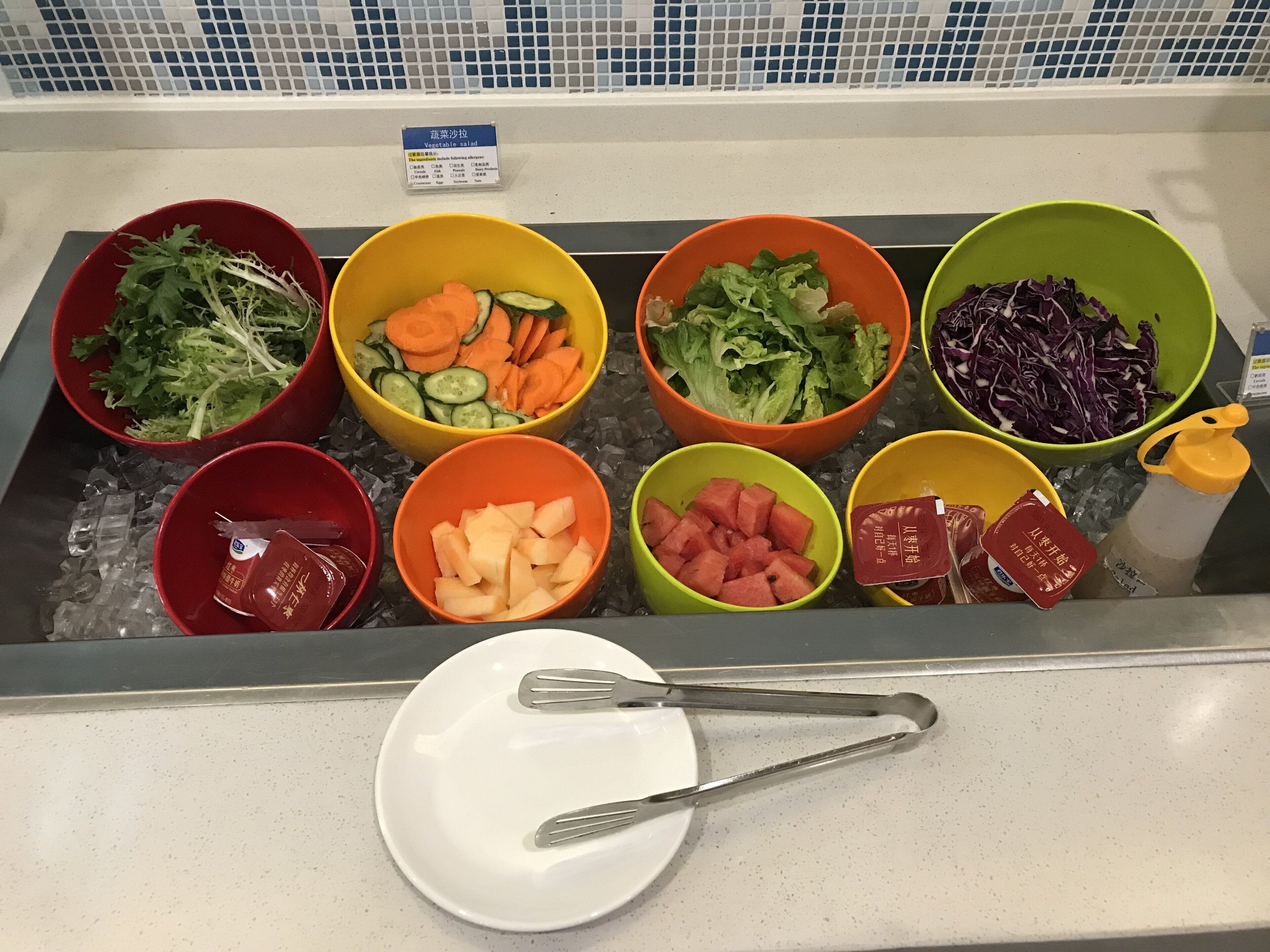 Una barra de ensaladas con diversas verduras y aderezos.
