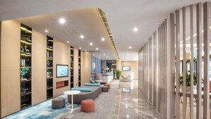 Un moderno vestíbulo de hotel con recepción, zonas de estar y un largo pasillo.