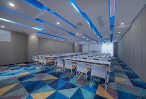 A conference room with a long table, chairs, and a projector screen.
