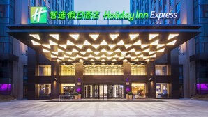 A Holiday Inn Express hotel entrance with a modern design, featuring a geometric patterned roof and a prominent signage.