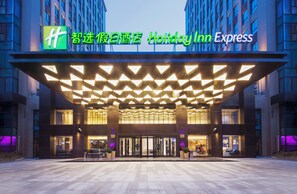 A Holiday Inn Express hotel entrance with a modern design, featuring a geometric patterned roof and a prominent signage.