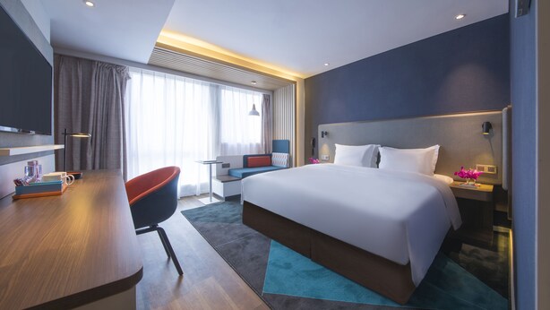 A modern hotel room with a large bed, a desk, a chair, and a TV. - Holiday Inn Express Shanghai Jinshan by IHG (Shanghai)