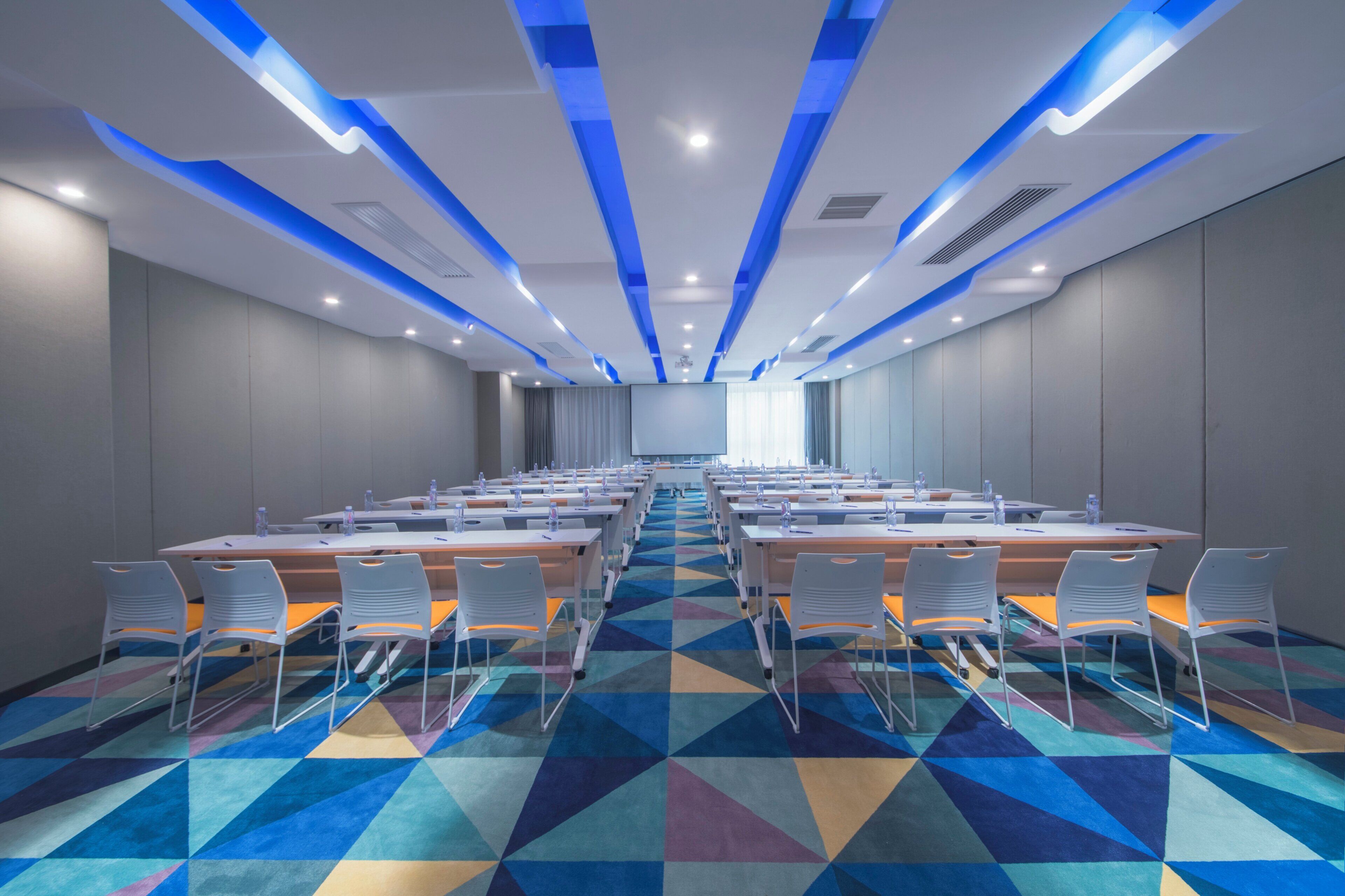 A conference room with a long table, chairs, and a patterned carpet.