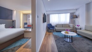 A modern hotel room with a large bed, a sofa, a coffee table, and a TV. - Holiday Inn Express Shanghai Jinshan by IHG (Shanghai)