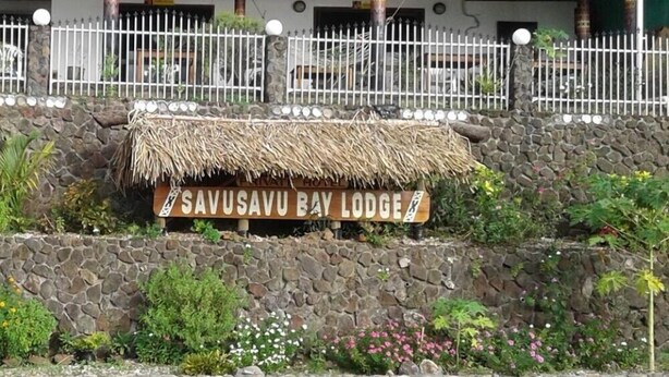 Señal del Savusavu Bay Lodge, con techo de paja y pared de piedra.