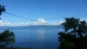 Vista de un lago tranquilo con una carretera en primer plano y árboles a la derecha.