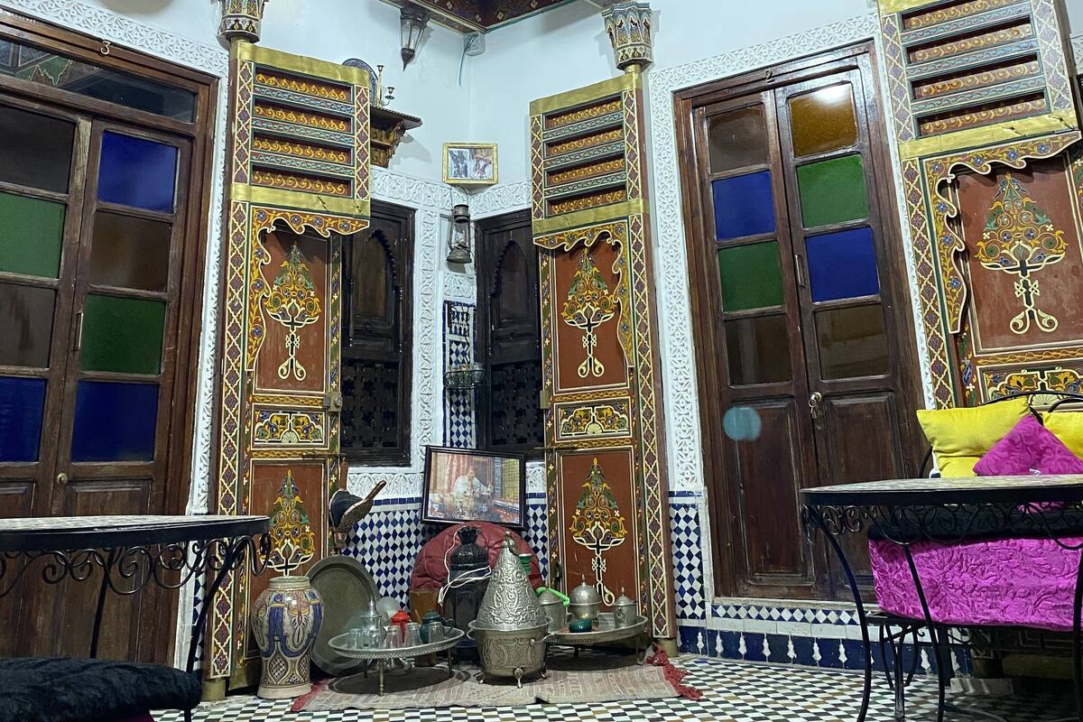A room with ornate ceiling patterns, wooden doors with glass panels, and a checkered floor.