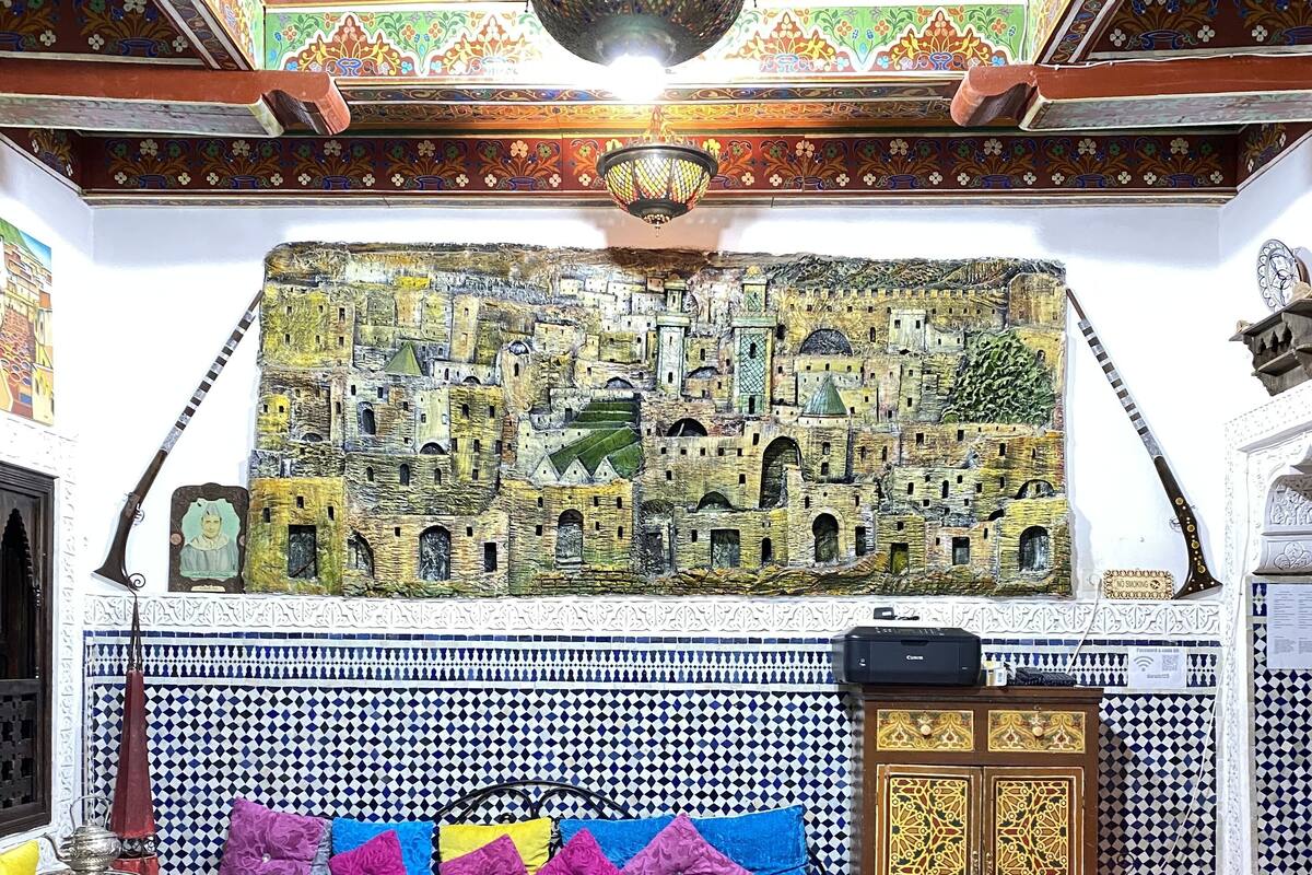 A room with a patterned floor, a sofa with colorful cushions, a hanging lamp, and a wall with a detailed mural.