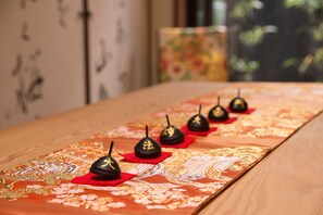 A table with a patterned tablecloth and several small, dark objects with gold characters on red bases.