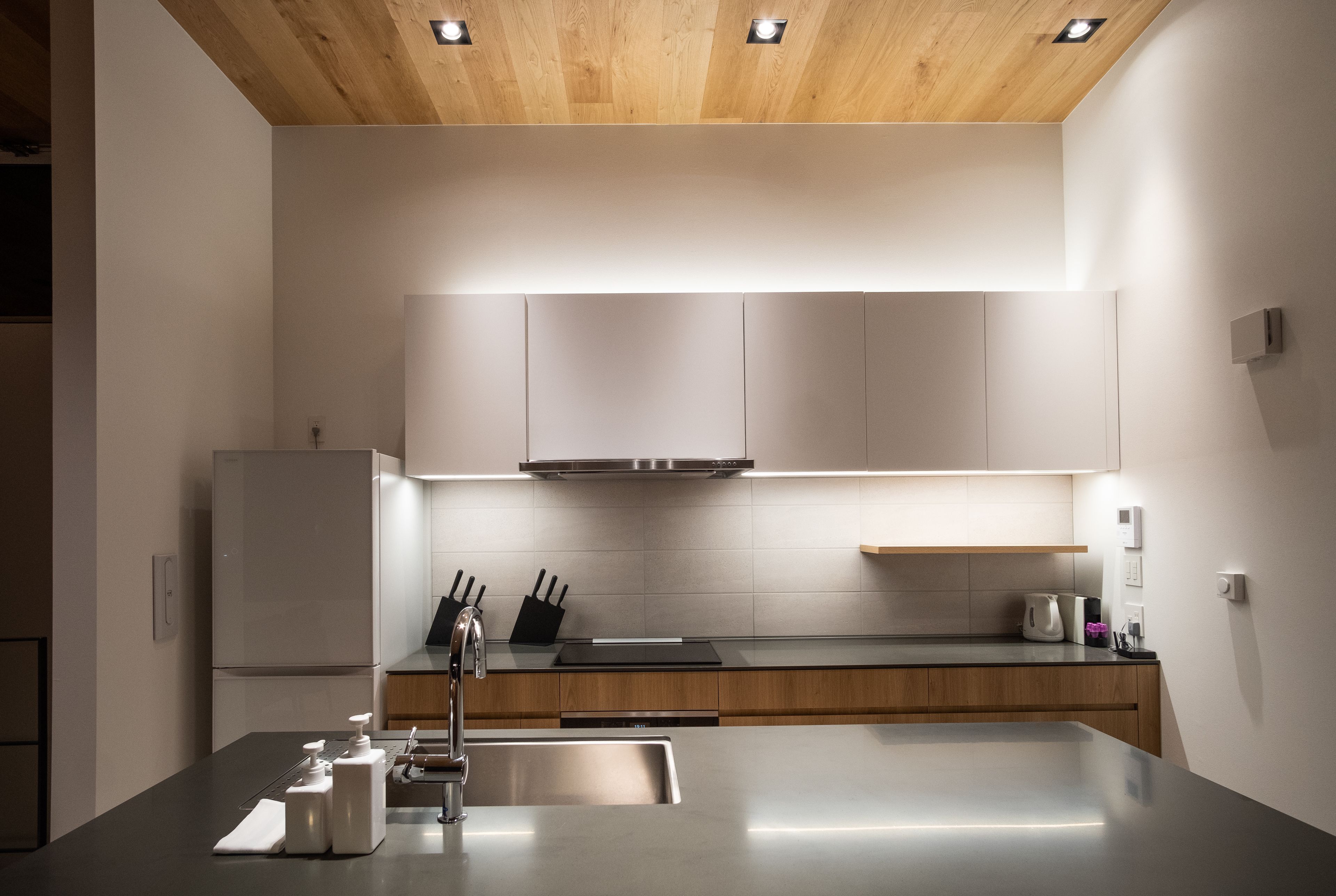 A modern kitchen with a stainless steel refrigerator, wooden cabinets, and a sleek countertop.
