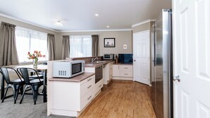 A modern kitchen with white cabinets, a microwave, a sink, and a refrigerator. - Quiet Napier Retreat, close to the off-road trails (Taradale)