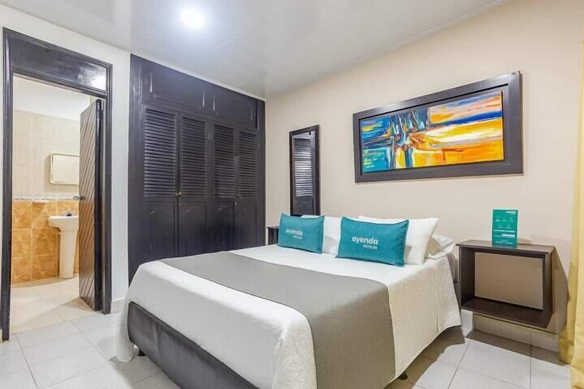 Une chambre d’hôtel avec un lit, un tableau au mur et une table de chevet.