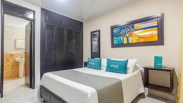 Une chambre d’hôtel avec un lit, un tableau au mur et une table de chevet.