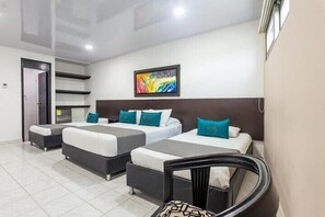 Habitación de hotel con dos camas, un sofá, una silla y un cuadro en la pared.