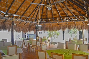 Un restaurante con techo de paja, mesas y sillas de madera.